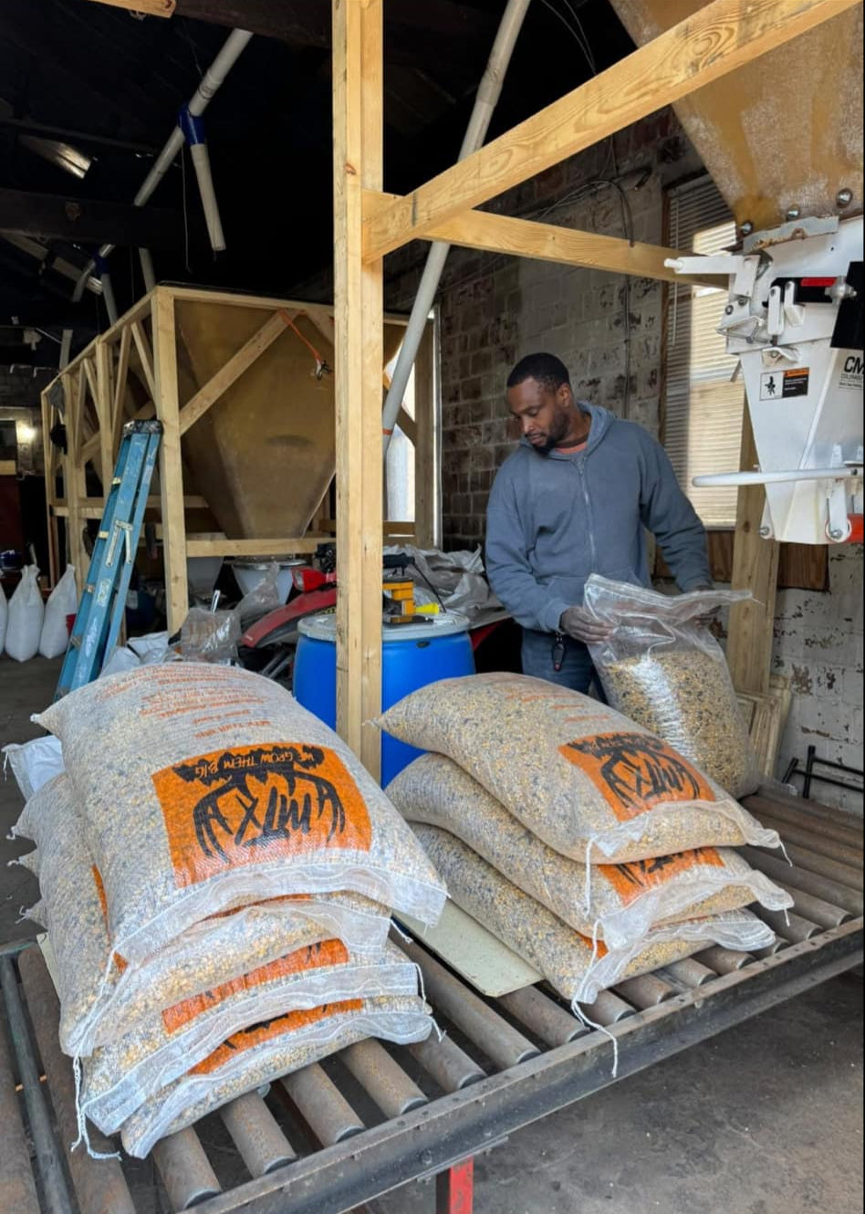 A palletized warehouse setting with multiple bags of MTX Trail Mix deer feed arranged in rows.