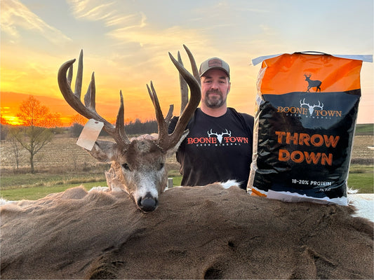 Man standing next to a large deer with a Boone & Crockett Throw Down bag in the foreground.