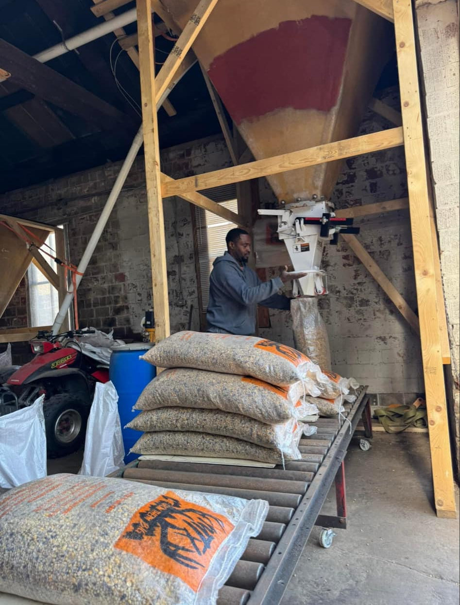 A palletized warehouse setting with multiple bags of MTX Trail Mix deer feed arranged in rows.