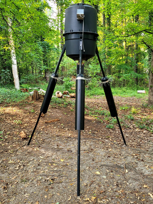 deer feeder with spring sliders  protecting the feed from raccoons on a tripod stand 